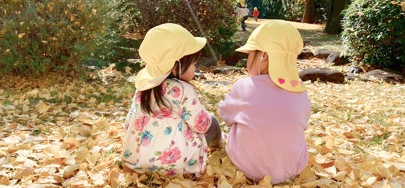 落ち葉の上に座る子どもたち